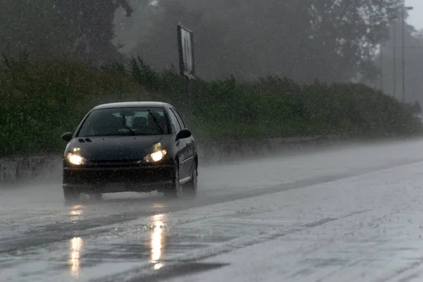 Den starka stormen med kraftigt regn på vägen med dålig synlighet av bilar. Begreppet risk för körning i dåligt väder Stockfoto