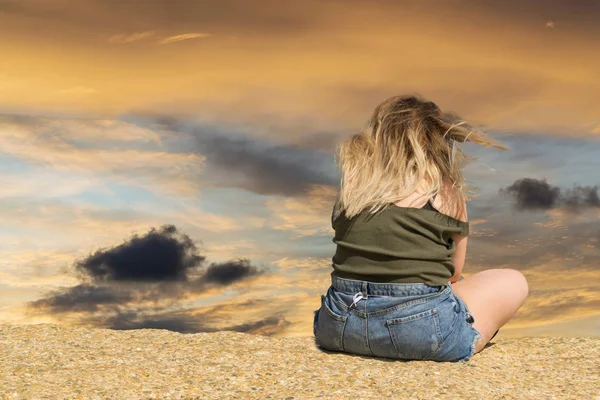 Jovem mulher sentada e olhando para frente para um céu à noite com nuvens. A imagem com um lugar para texto, espaço de cópia — Fotografia de Stock