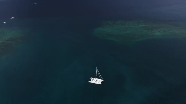 Luchtfoto van een verankerd catamaran jacht staande en mensen kunnen zonnebaden op het dek. — Stockvideo