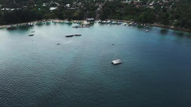 Вид с воздуха на стоящую на якоре катамаранскую яхту и люди могут загорать на ее палубе . — стоковое видео