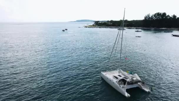 Vista aérea de um iate catamarã ancorado de pé e as pessoas podem tomar sol em seu convés . — Vídeo de Stock