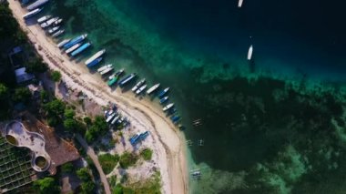 Berrak ve turkuaz su ile koyda demirlemiş teknelerin havadan drone görünümü.