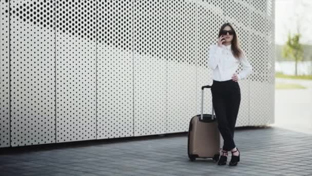 La mujer tiene una llamada con su equipaje en el aeropuerto — Vídeos de Stock