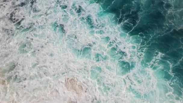 Abstraktní letecký pohled na mořské vlny, které se hroutí na skalnaté pobřeží