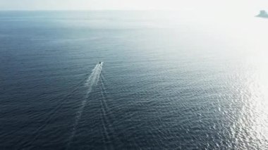 Tekne ile güneş ışığını yansıtan derin mavi deniz dalgalanan su yüzeyi.