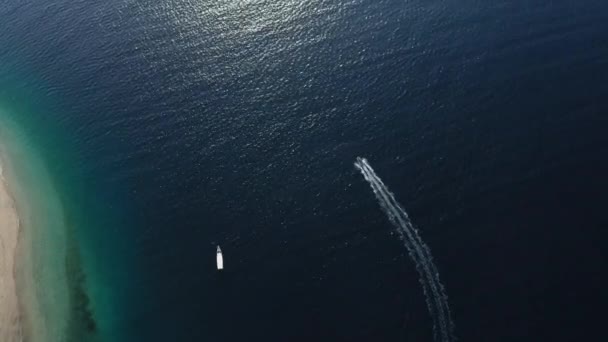 Tekne ile güneş ışığını yansıtan derin mavi deniz dalgalanan su yüzeyi. — Stok video