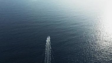 Tekne ile güneş ışığını yansıtan derin mavi deniz dalgalanan su yüzeyi.