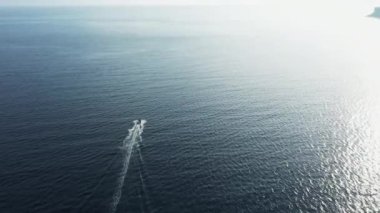 Tekne ile güneş ışığını yansıtan derin mavi deniz dalgalanan su yüzeyi.