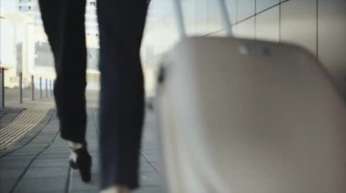 Başarılı kız bagaj talep alanında tekerlekler üzerinde bir bavul rulo.