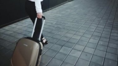 Başarılı kız bagaj talep alanında tekerlekler üzerinde bir bavul rulo.