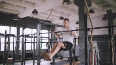 Gövdesi fit ve elleri güçlü beyaz erkek sporcu dışarıda barfiks çekiyor. Yakışıklı sarışın sporcu stadyum yatay barına yanaşıyor. Metin ol bar egzersizleri..
