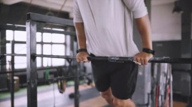 Gövdesi fit ve elleri güçlü beyaz erkek sporcu dışarıda barfiks çekiyor. Yakışıklı sarışın sporcu stadyum yatay barına yanaşıyor. Metin ol bar egzersizleri..