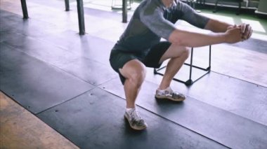 Erkek fitness eğitmeni modern plase de squat egzersiz gösteren.