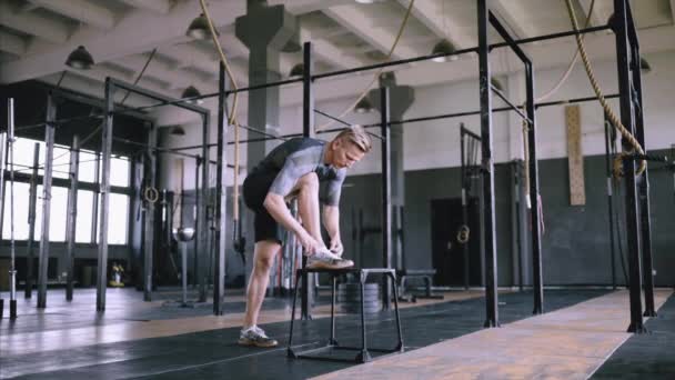 Hombre atando cordones en el gimnasio — Vídeos de Stock