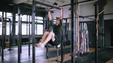 Terleyen kas adam spor salonunda antrenman yapıyor, kaslı adam dizini kaldırıyor.