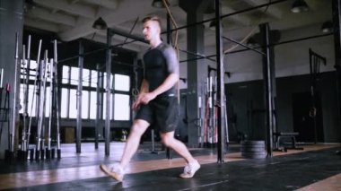 Çekici kas adam spor salonunda egzersiz ve antrenman yapıyor, kas yığını hareketleniyor.