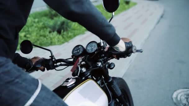 Μηχανόβιος με δερμάτινα γάντια και μαύρη κουκούλα ξεκινά μοτοσικλέτα. — Αρχείο Βίντεο