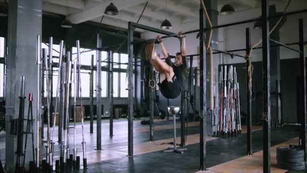 Levantar los pies hasta el bar en la barra de gimnasio, ejercicio atractivo hombre muscular y entrenar en el gimnasio — Vídeo de stock