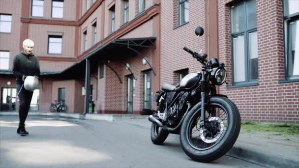 Biker goes to his cool and custom motorcycle in a big city — Stock Video