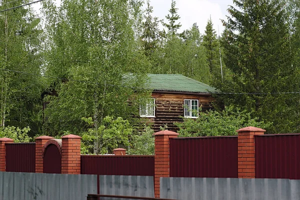 wooden country house behind a fence in the forest