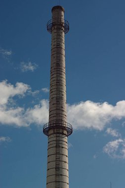 Bulutlu mavi gökyüzüne karşı fabrika bacası