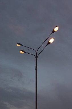 Alacakaranlık gökyüzüne karşı elektrik lambalı bir direk.