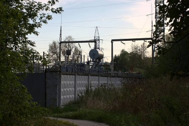 Çitlerin arkasındaki elektrik santrali ağaçların arasında.