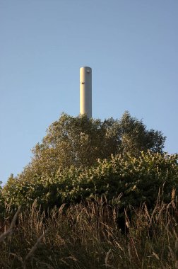 Kazan dairesinin bacası tepedeki ağaçların üzerinden yükseliyor.