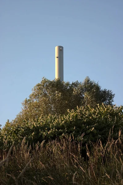 Kazan dairesinin bacası tepedeki ağaçların üzerinden yükseliyor.