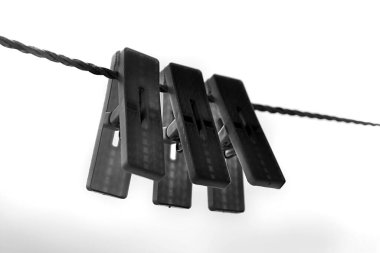 Eski bir çamaşır ipinde üç plastik mandal.