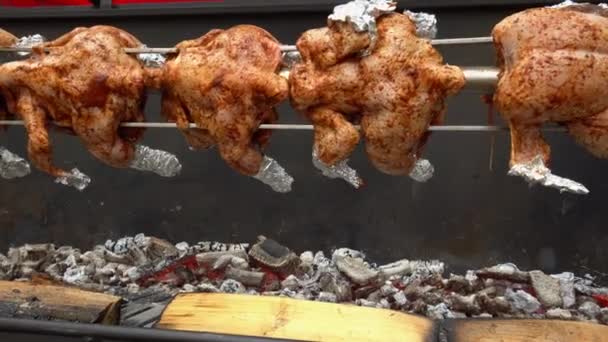 Chicken roasted on spit being grilled over the bright glowing coals — Stock Video