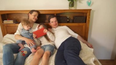 Çocuklu ebeveynler yatakta eğlenirler. El hareket çekimi