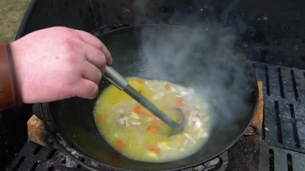 Deliciosa sopa hirviendo en olla mezclada con cuchara de acero. Cámara lenta de mano — Vídeo de stock