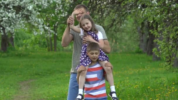 Hombre con dos niños niño y niña se divierten en el jardín de primavera. Movimiento lento — Vídeos de Stock