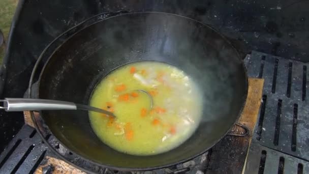 Суп з овочами і м'ясом кип'ятять у горщику на грилі для барбекю. Портативний постріл . — стокове відео