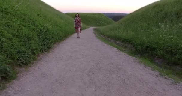 砂利道を歩くカラフルなドレスでアクティブな女の子。ハンドヘルドショット. — ストック動画