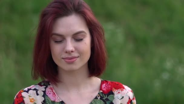 Fiatal vörös hajú nő nyitott szemmel és mosollyal a kamerába néz — Stock videók