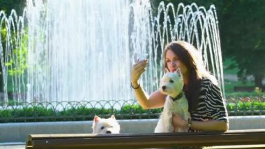kız ve iki sevimli köpek park çeşme yakınında selfie için poz. Birlikte en iyi arkadaşlar