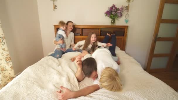 Freche Familienkinder mit Mutter klettern auf Vater zurück ins Bett. Handschuss — Stockvideo