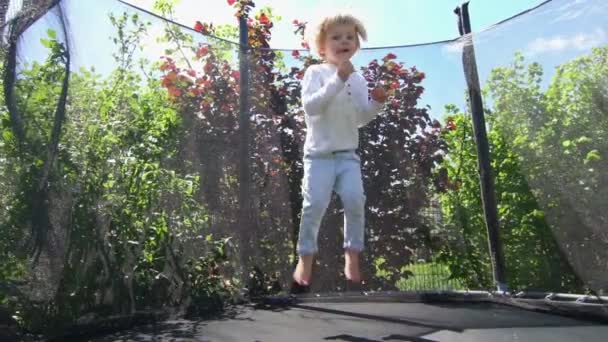 Niño travieso saltar en trampolín con red protectora. Movimiento lento 100fps — Vídeos de Stock