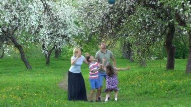 Aktif aile bahar bahçesinde topla oynar. Statik yavaş çekim.