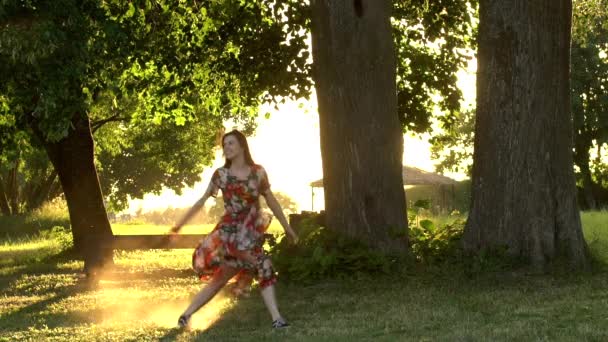 Femme heureuse sauter dans le parc sur la lumière du coucher du soleil. Statique au ralenti 100fps tir . — Video