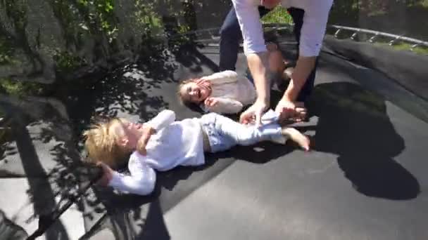 Homem ativo com menino e menina se divertir no trampolim no quintal. Tiro portátil — Vídeo de Stock