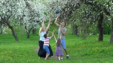Aktif aile bahar bahçesinde topla oynar. Çocuklu mutlu ebeveynler