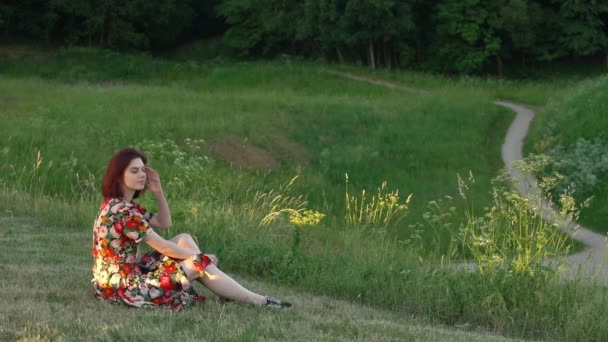 Jolie femme rousse assise sur l'herbe. Plan statique . — Video