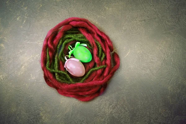 赤と緑のウール ロゴやテキストのためのスペースと暗い背景にイースターの卵と巣します — ストック写真