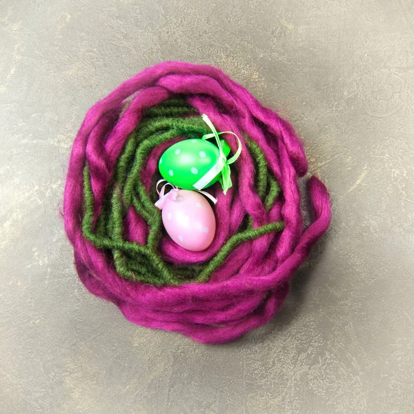 背景上的紫罗兰和绿色毛线巢 — 图库照片