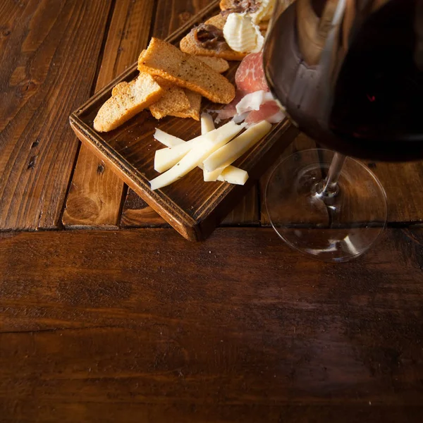 Italian food on a wooden chopping with a red wine glass. — Stock Photo, Image