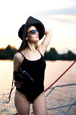 Siyah şapkalı, güneş gözlüklü ve mayolu güzel bir kız.