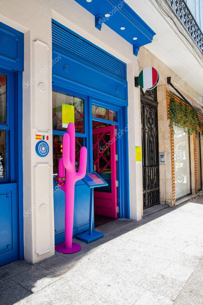 A cafe with a vivid and artistic facade. A stylish restaurant entrance with a pink cactus statue. Madrid Spain 08.06.2025